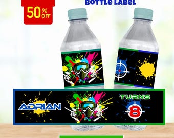 Puede incluir: Etiquetas de botellas de agua imprimibles con un tema de paintball. Las etiquetas presentan un fondo negro con salpicaduras de pintura de colores, una máscara de paintball y el texto "Adrian" y "Turns 8".