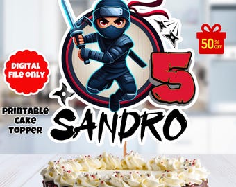 May include: Printable cake topper featuring a cartoon ninja character holding a sword, a red circle with the number 5, and the name Sandro. The topper is on a cake with white frosting and chocolate drizzle.