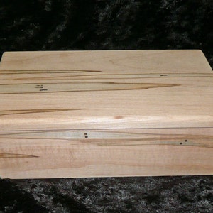May include: A wooden box with a light brown finish and a natural wood grain pattern. The box has a hinged lid and is made of maple wood.