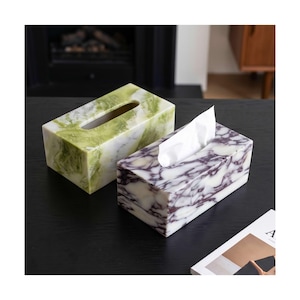 May include: Two rectangular tissue box covers made of polished stone. One box features a vibrant green and white marbled pattern, while the other displays a deep purple and white marbled design with a white tissue protruding from the top slot.