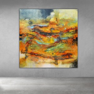 May include: Large abstract painting with a textured surface. The artwork features a landscape of warm colours, including orange, yellow, and red, with accents of blue and black. The painting is displayed on a grey wall.