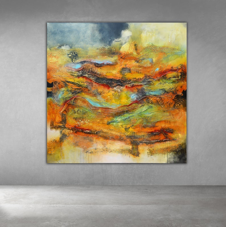 May include: Large abstract painting with a textured surface. The artwork features a landscape of warm colours, including orange, yellow, and red, with accents of blue and black. The painting is displayed on a grey wall.