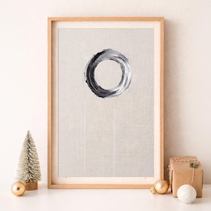 Puede incluir: Una lámina enmarcada con una pincelada circular negra y gris centrada sobre un fondo beige claro texturizado. El texto PERFECT CHRISTMAS GIFT aparece sobre el marco. Un pequeño árbol de cepillo y una caja de regalo están situados al lado.