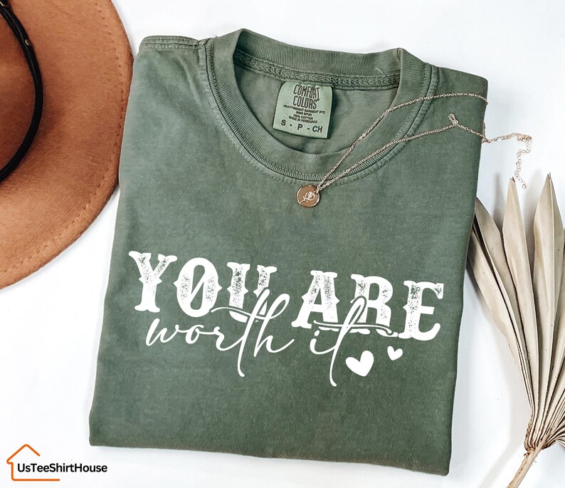 May include: A green t-shirt with the text "YOU ARE worth it" in white with a distressed look. Two small white hearts are to the right of the text.