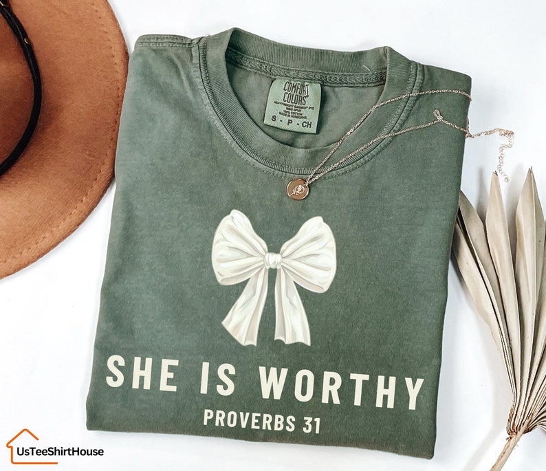 May include: A green t-shirt with a white bow and the text "SHE IS WORTHY PROVERBS 31" in white.