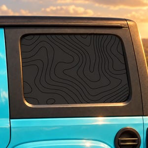 May include: A matte black window decal featuring a topographic map design with thin, flowing lines applied to the rear side window of a bright blue vehicle. The decal covers the entire glass surface, creating a dark, textured appearance.