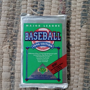 May include: A silver foil pack of 1999 Major League Baseball cards. The pack features a green background with a baseball logo and the text "1999 Edition". The pack also includes a hologram and a "Win!" offer for four 1991 season tickets.
