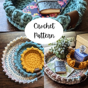 May include: Three crocheted baskets in different sizes and colors. The largest basket is white, brown, and blue. The medium basket is blue. The smallest basket is yellow. The baskets are on a wooden surface.