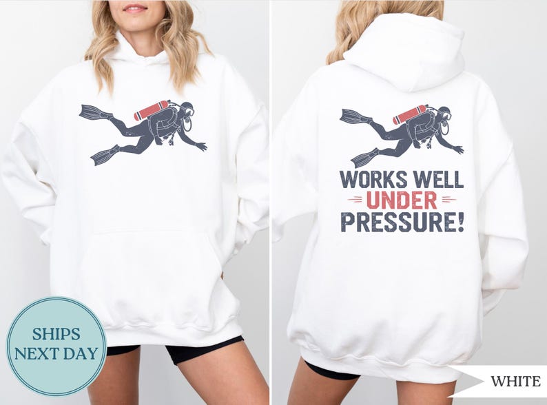 A white hoodie with a graphic of a scuba diver and the text "WORKS WELL UNDER PRESSURE!" printed on the back.