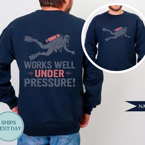 Navy sweatshirt with a graphic of a scuba diver and the text "WORKS WELL UNDER PRESSURE!"