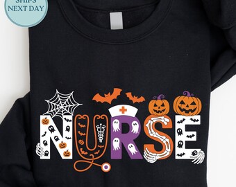 May include: Black Halloween-themed sweatshirt with the word "NURSE" in white, orange, and purple. The design includes a spiderweb, bats, pumpkins, ghosts, and a stethoscope. The word "BLACK" is printed in the upper right corner.