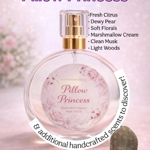 May include: A clear glass perfume bottle with a gold sprayer, labeled "Pillow Princess." The bottle features a floral design and a list of scents: Fresh Citrus, Dewy Pear, Soft Florals, Marshmallow Cream, Clean Musk, and Light Woods. The text "Handcrafted Fragrance Made in USA" is also visible.