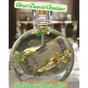 Può includere: Una bottiglia di vetro trasparente con un tappo dorato e un tappo dorato. La bottiglia è riempita con un liquido trasparente e contiene una banconota da un dollaro, scaglie d'oro e cristalli verdi. La bottiglia è etichettata "The Financial Freedom Elixir Botanical and Crystal Infused Perfume".