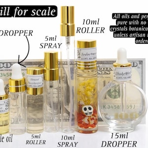 May include: Assortment of perfume bottles and sample oils, including 3ml, 5ml, 10ml, and 15ml sizes. The bottles have gold caps and labels. The text on the image says "All oils and perfumes come pure with no handmade crystals botanicals inclusions."