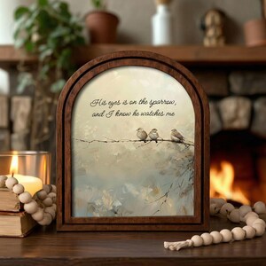 May include: Wooden framed art print featuring three small birds perched on a branch. The artwork has a soft, muted color palette with a quote: "His eyes is on the sparrow, and I know he watches me."