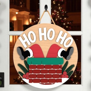 May include: A round wooden Christmas sign with the words "HO HO HO" in white. Santa's legs and feet are seen coming out of a chimney. The chimney is made of red bricks, with green and red accents. A rope is used for hanging.