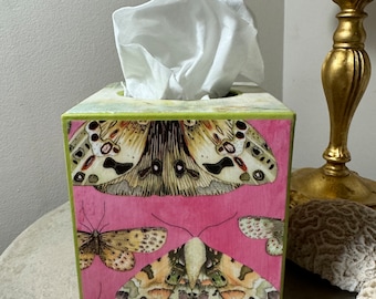 May include: A pink tissue box cover with a green top and a design of butterflies. The butterflies are in shades of brown, white, and green.