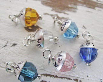 May include: Six silver charm pendants with crystal beads. Each pendant has a different color crystal and a personalized inscription. The inscriptions include "Ray", "Em", "No", "Kay", "Zo", and "Lo".