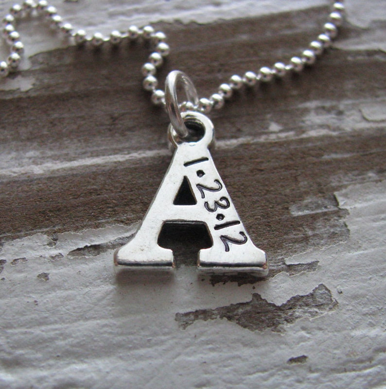 Peut inclure: Collier en argent avec un pendentif en forme de lettre A. Le pendentif porte la date 1.23.12 grav&eacute;e.