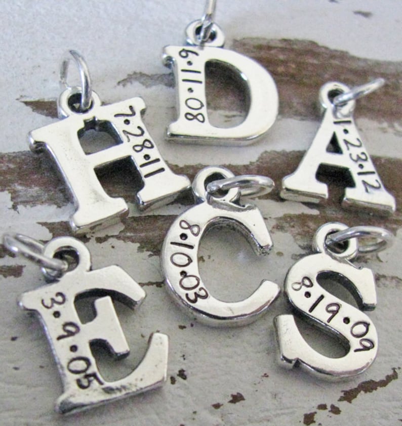Peut inclure: Breloques en argent en forme de lettres avec des dates grav&eacute;es sur chaque breloque. Les lettres sont H, D, A, C, E et S. Les dates sont 7-28-11, 6-11-08, 1-23-12, 8-10-03, 3-9-05 et 8-19-09.