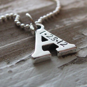 Peut inclure: Collier en argent avec un pendentif en forme de lettre A. Le pendentif porte la date 1.23.12 grav&eacute;e.