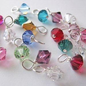 Peut inclure: Assortiment de perles en cristal colorées avec des boucles en fil d'argent. Les perles sont dans différentes nuances de rouge, rose, bleu, vert et transparent.