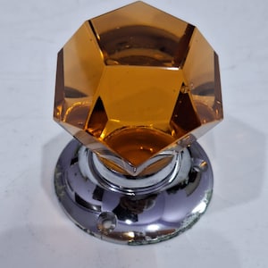 May include: An amber glass door knob with a faceted design and a chrome base.