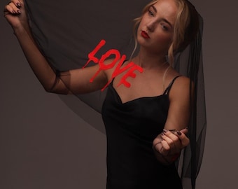 Zwarte gotische bruidssluier met rode 'Love'-borduurwerk, een alternatief donker bruidsaccessoire.