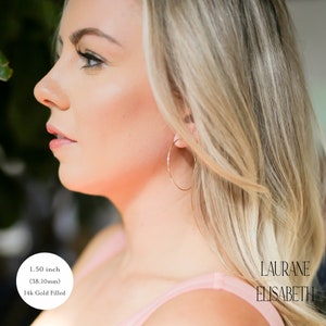model wearing 1.50 inch 14k gold filled thin hoop earrings.  threader earrings. Laurane Elisabeth specializing in delicate, lightweight handmade, minimalist earring designs available in 14k gold filled, 14k rose gold filled and 925 sterling silver. nickel free threader earrings.