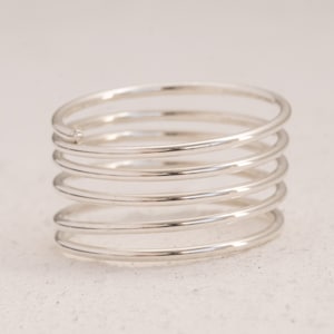 May include: A silver ring with five bands stacked on top of each other. The ring has a small diamond set in the top band.