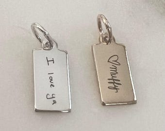 May include: Two rectangular metal charms with jump rings. The left charm is silver-toned and engraved with the text I love ya. The right charm is gold-toned and engraved with a heart symbol followed by the text Muffy in a cursive script font.