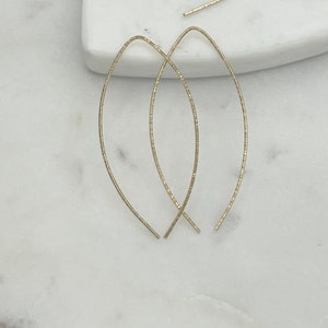 May include: A pair of gold-toned, thin, wire earrings with a curved, oval shape.