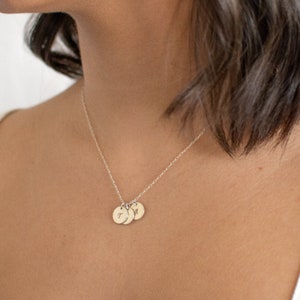 May include: A silver chain necklace with three small silver discs, each with a letter engraved on it. The letters are 'T', 'J', and 'N'.