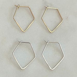 May include: Four pairs of geometric hoop earrings. Two pairs are gold and two pairs are silver. The earrings are all in the shape of a diamond.