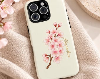 May include: A cream-colored smartphone case featuring a detailed illustration of a blooming cherry blossom branch with pink flowers and buds. The name Alexandria is printed in elegant gold script lettering next to the floral design.