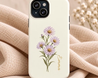 May include: A cream-colored smartphone case featuring a central illustration of a bouquet of light purple daisy-like flowers with green stems and leaves. The name Emma is printed in a gold cursive script to the right of the floral design.