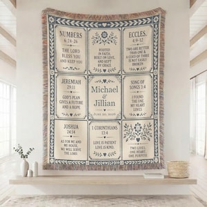 May include: Cream-coloured woven throw blanket with a blue floral and text design. The blanket features Bible verses and the names "Michael & Jillian" with a wedding date. The blanket has a fringed edge.