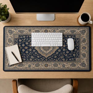 May include: A rectangular desk mat featuring a dark blue background with an intricate, repeating floral and paisley pattern in shades of beige, cream, and light blue, bordered by a decorative frame that mimics a traditional woven rug design.