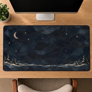 May include: A rectangular desk mat featuring a dark blue and black mosaic-style landscape of rolling hills and pine trees under a night sky. The scene includes a crescent moon and several small, four-pointed gold stars scattered across the dark surface.