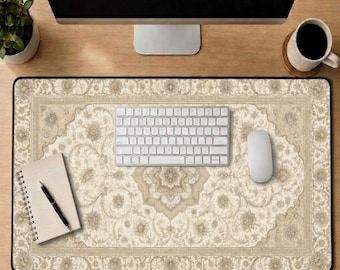 May include: A rectangular desk mat featuring a beige and cream-colored intricate floral pattern reminiscent of a traditional rug. The mat is positioned on a wooden surface beneath a white computer keyboard, a white computer mouse, and a notebook.