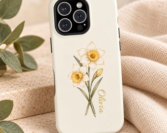 May include: A cream-colored smartphone case featuring a botanical illustration of two yellow and white daffodils with green stems and leaves. The name Olivia is printed in a gold cursive script next to the floral design.