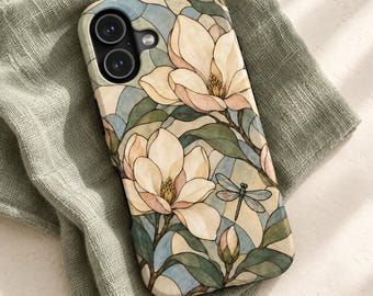 May include: A smartphone case featuring a stained glass style pattern of cream-colored magnolia flowers, green leaves, and a small dragonfly. The design incorporates soft blue and beige geometric segments, with a black camera lens cutout.