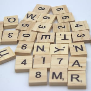Può includere: Una collezione di tessere di lettere in legno con lettere nere. Le tessere sono disposte in uno schema casuale e includono lettere come W, O, M, N, Y, T e numeri come 1, 2, 3, 4, 5, 6, 7, 8.