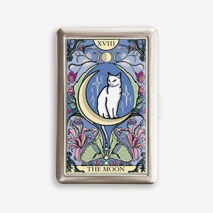May include: A silver metal case featuring a tarot card design. The card depicts a white cat on a crescent moon, surrounded by stars and floral elements, with the text "THE MOON" and "XVIII". The background is blue with purple and pink accents.