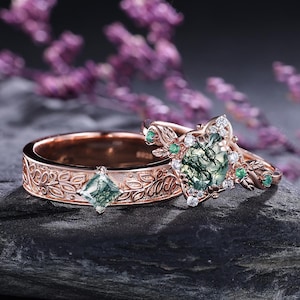 Puede incluir: Dos anillos de oro rosa con intrincados diseños florales y piedras verdes. Uno presenta una piedra verde de corte cuadrado, mientras que el otro tiene un engaste más elaborado con una piedra verde central, diamantes y esmeraldas.
