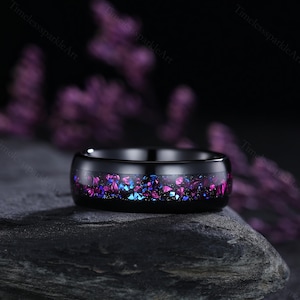 May include: A black tungsten carbide ring with a band of purple and blue glitter embedded in the metal.
