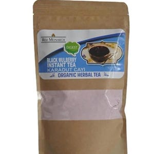Könnte beinhalten: Ein brauner Papierbeutel mit Instant-Tee. Auf dem Etikett steht "Black Mulberry Instant Tea Karadut Cayi Organic Herbal Tea" mit einem Bild von Tee in einer Tasse. Die Marke ist "Roi Monarch" mit dem Wort "Digest" in einem grünen Blatt.