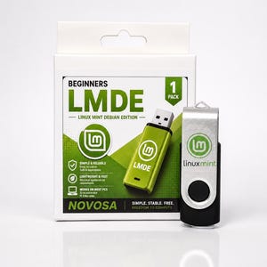 Könnte beinhalten: Eine weiße Pappschachtel für Linux Mint Debian Edition mit grüner Aufschrift und Texten wie BEGINNERS, LMDE und 1 PACK. Neben der Schachtel steht ein schwarzer und silberner USB-Stick mit dem aufgedruckten Linux Mint Logo und Schriftzug.
