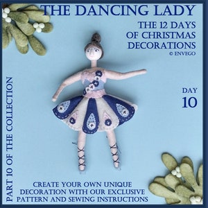May include: A felt ballerina doll with a blue and white dress, holding a pose with her arms outstretched. The doll is part of a 12-day Christmas decoration collection, day 10, called "The Dancing Lady".