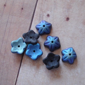 May include: Eight star-shaped polymer clay beads in shades of blue and black. The beads have a metallic sheen and are perfect for jewelry making.